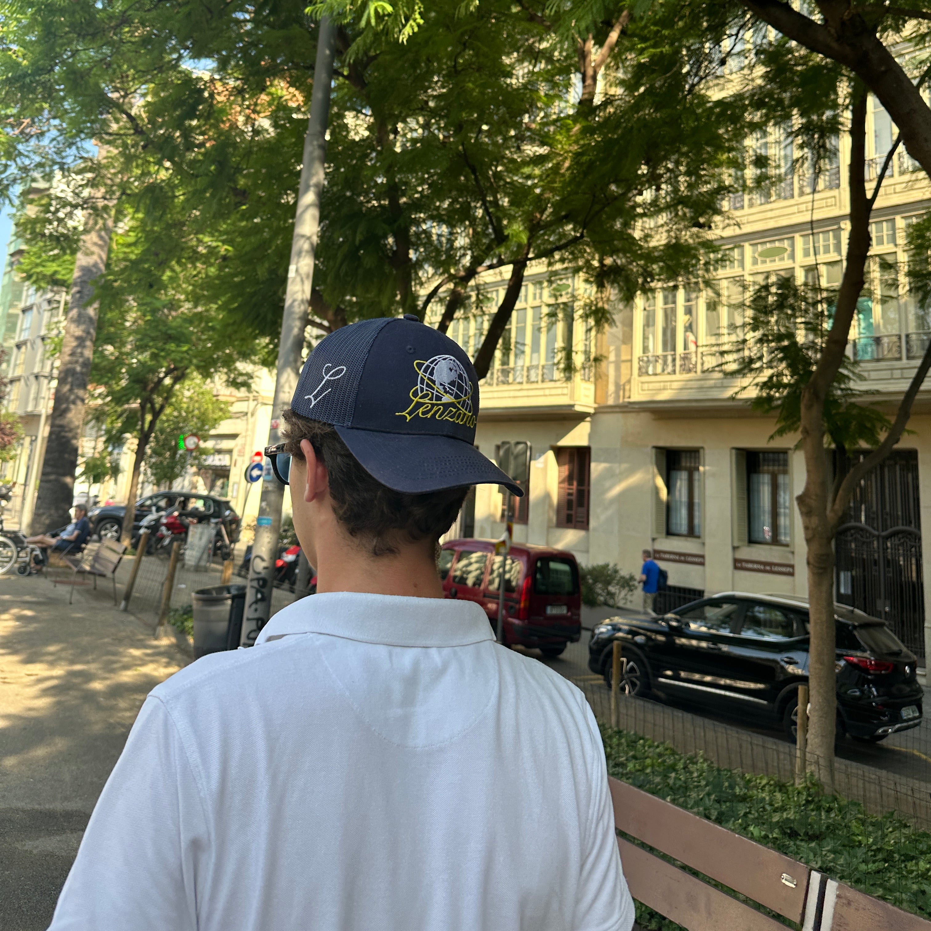 Person wearing a cap with trees and buildings in the background