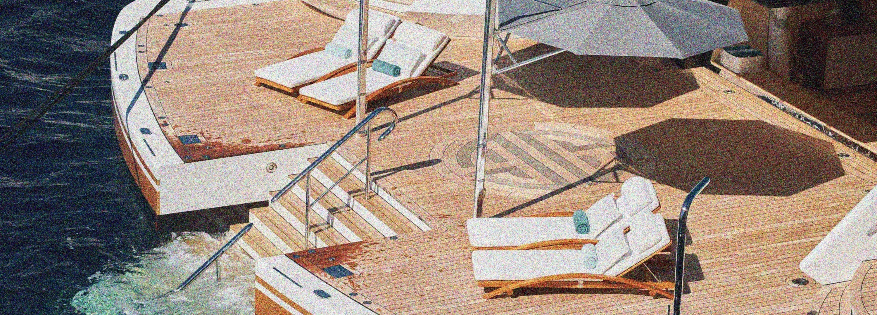 Yacht with wooden deck, lounge chairs, and umbrellas on a body of water.